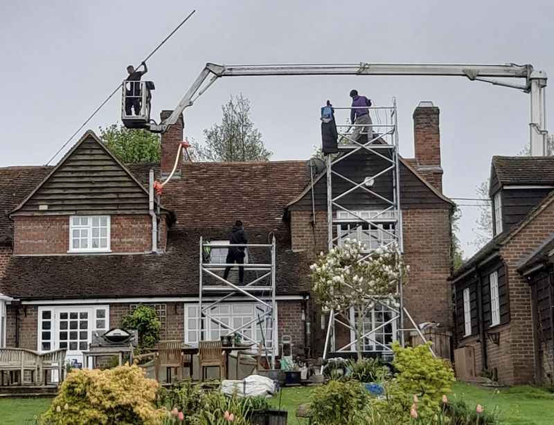 The Moss Cleaners using cherry picker and scaffolding to clean roof safely and professionally in Woking, Surrey